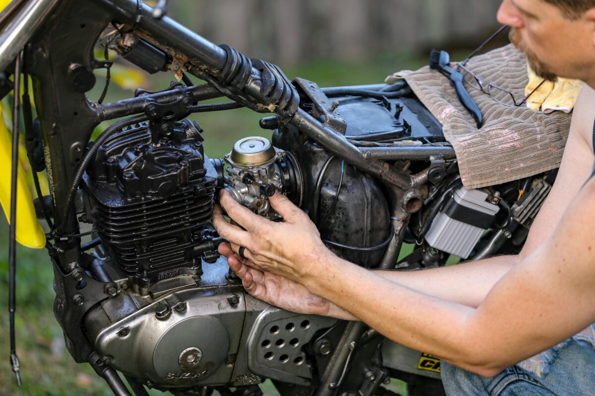 man fixing small engine on a motorcycle
